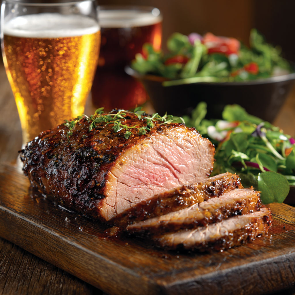 Une viande de boeuf grillée, servie avec une salade et une bière blonde.
