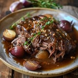 Un plat mijoté de viande, accompagné de morceaux d'oignons et de sauce parfumée, présenté sur une assiette