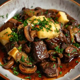 Un délicieux plat de bœuf mijoté garni de champignons, nappé de fromage et rehaussé d'une touche de persil frais.