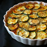 Un plat appétissant de tranches de courgettes gratinées avec une croûte de fromage dorée et une touche d’épices.