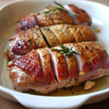 Rôti de magrets tranché avec croûte dorée, présenté avec huile et herbes fraîches.