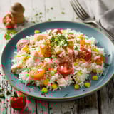 Une salade de riz et tomates avec des herbes vertes et des légumes.
