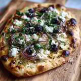 Une pizza naan avec des oignons et des épinards.