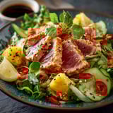 Une salade thon est servie sur un plateau avec des légumes frais et des fruits.