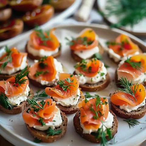 Plateau de petits toasts garnis de fromage crémeux et recouverts de fines tranches de saumon fumé, parés avec des herbes fraîches.
