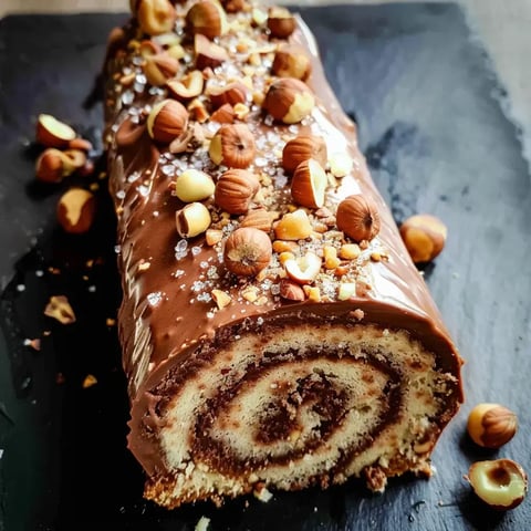 Un roulé au chocolat généreusement garni de noisettes grillées, présenté sur un plateau élégant.