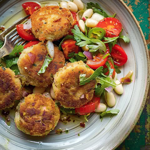 Un plat composé de haricots blancs, croquettes de sardines croquantes et tomates rôties.