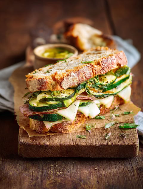 Un sandwich au café et au jus de citron, avec des légumes verts et du bacon.