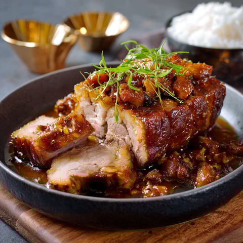 Une recette de porc est servie dans un bol sur une table.